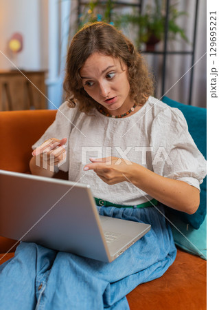 Angry stressed young Caucasian woman talking laptop using computer webcam video call on sofa at home Angry stressed young Caucasian woman talking laptop using computer webcam video call on sofa at home 129695221
