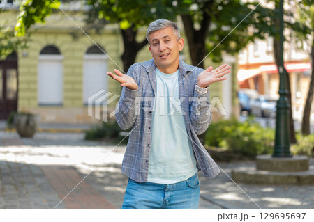 Upset mature man showing thumb down sign gesture, expressing dissatisfied bad work on city street Upset mature man showing thumb down sign gesture, expressing dissatisfied bad work on city street 129695697