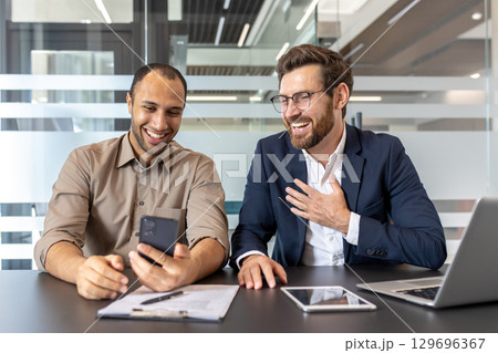 A lively meeting of two colleagues in a modern office, sharing a conversation while using a smartphone for collaboration. A lively meeting of two colleagues in a modern office, sharing a conversation while using a smartphone for collaboration. 129696367