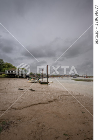 River Deben at low tide with small boats under a stormy sky. View towards the historic town of Woodbridge in Suffolk, UK. River Deben at low tide with small boats under a stormy sky. View towards the historic town of Woodbridge in Suffolk, UK. 129696677