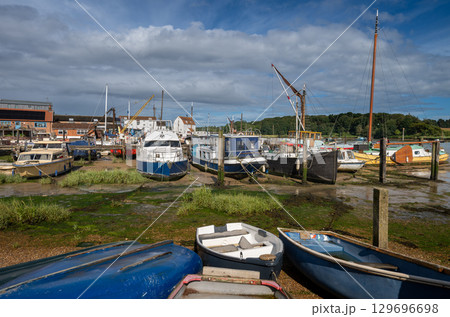 Small boats on a sunny day. View of the quay at low tide on the River Deben in the historic town of Woodbridge in Suffolk, UK. 129696698