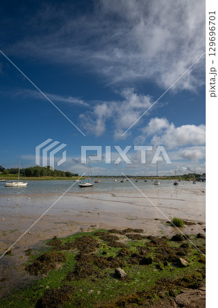 River Deben at low tide with small boats on a sunny day. View near the historic town of Woodbridge in Suffolk, UK. River Deben at low tide with small boats on a sunny day. View near the historic town of Woodbridge in Suffolk, UK. 129696701