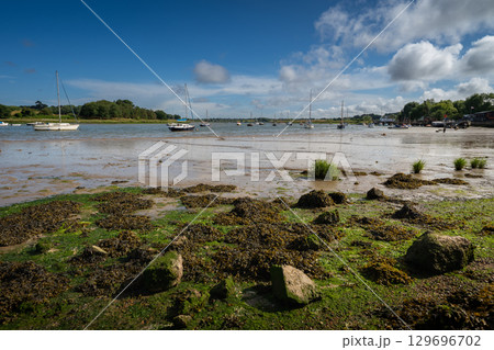 River Deben at low tide with small boats on a sunny day. View near the historic town of Woodbridge in Suffolk, UK. River Deben at low tide with small boats on a sunny day. View near the historic town of Woodbridge in Suffolk, UK. 129696702