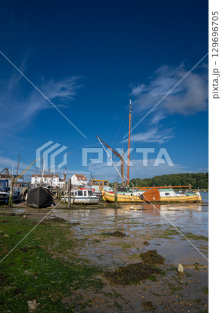 Boats on a sunny day at the quay in the historic town of Woodbridge in Suffolk, UK. View at low tide on the River Deben. 129696705