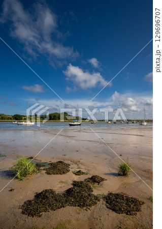 River Deben at low tide with small boats on a sunny day. View near the historic town of Woodbridge in Suffolk, UK. 129696707