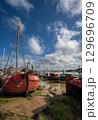 Boats sitting on mud under a stormy sky. View of the quay at low tide on the River Deben in the historic town of Woodbridge, Suffolk, UK. 129696709