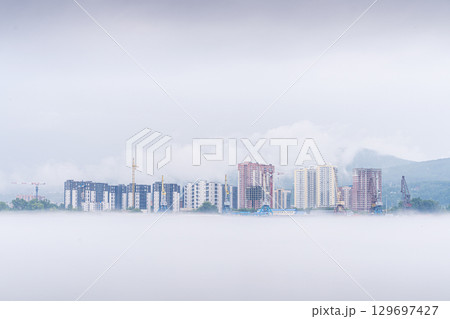 Misty conditions blanket a residential neighborhood adjacent to the Yenisei River in Krasnoyarsk. New buildings rise prominently, their outlines partially obscured by fog. 129697427