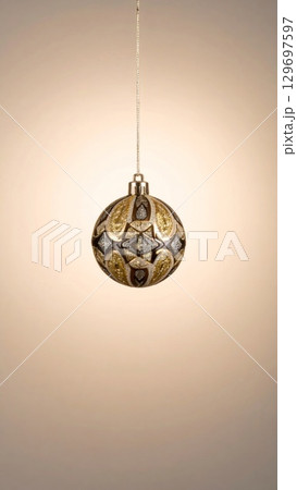 Elegant Gold and Silver Christmas Bauble Hanging Ornament Against Warm Background 129697597