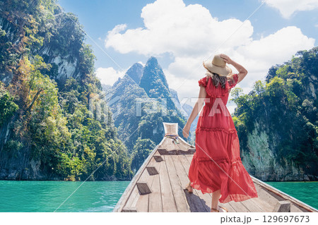 Travel to famous famous places in Thailand - Breathtaking landscapes of Cheow Lan Lake in Khao Sok National Park, Thailand with a solo female traveler in a vibrant red dress and wide brimmed hat on 129697673