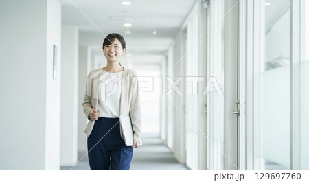 廊下を歩く女性ビジネスパーソン 129697760