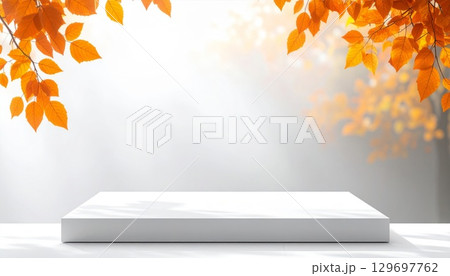 Minimalist White Display Podium with Soft Autumn Leaves and Bright Natural Lighting 129697762