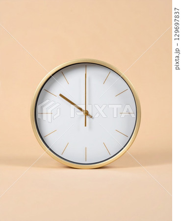 Close Up View of Round White Clock with Gold Frame on Beige Background Close Up View of Round White Clock with Gold Frame on Beige Background 129697837