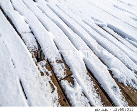 Snow Covered Wooden Deck Boards with Brown Wood Grain Detail in Winter Snow Covered Wooden Deck Boards with Brown Wood Grain Detail in Winter 129698013