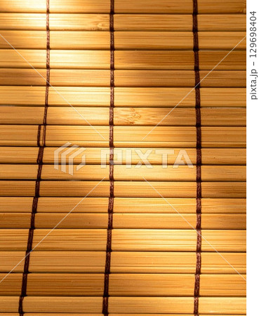 Closeup of Light Brown Bamboo Mat with Woven Pattern Texture Background with Natural Light 129698404