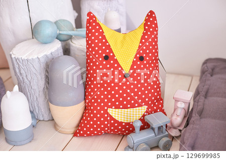 Cute red polka dot fox pillow with soft pastel toys in cozy children s playroom Cute red polka dot fox pillow with soft pastel toys in cozy children s playroom 129699985