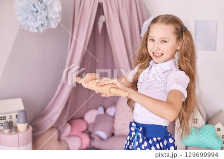 Caucasian female child baking pretend play in bedroom with rolling pin Caucasian female child baking pretend play in bedroom with rolling pin 129699994