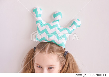 Young caucasian girl with chevron crown pillow on head playful pose Young caucasian girl with chevron crown pillow on head playful pose 129700111