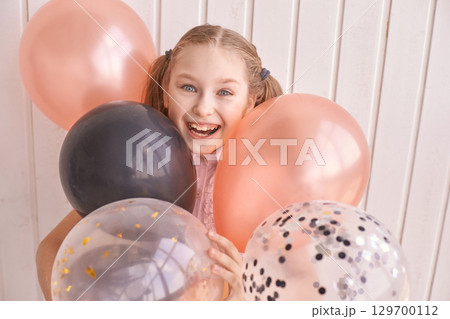 Joyful caucasian young girl with balloons in vibrant celebration setting against Joyful caucasian young girl with balloons in vibrant celebration setting against 129700112