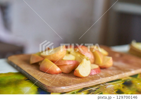 Freshly sliced red apples on wooden cutting board in a kitchen setting Freshly sliced red apples on wooden cutting board in a kitchen setting 129700146