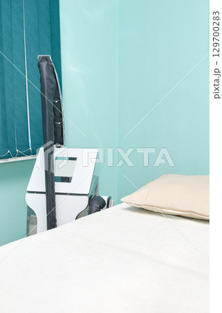 Empty modern clinic room with white bed and advanced medical equipment in clean 129700283
