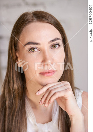 Caucasian young adult female with long brown hair and subtle makeup posing 129700404