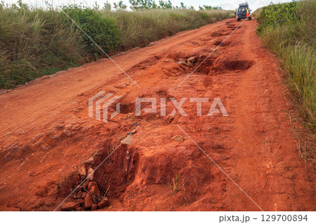 Red dust and mud road in poor condition with large holes and bumps formed after rain. Routes to Andringitra national park are extremely bad during wet season in region near Sendrisoa, Madagascar Red dust and mud road in poor condition with large holes and bumps formed after rain. Routes to Andringitra national park are extremely bad during wet season in region near Sendrisoa, Madagascar 129700894