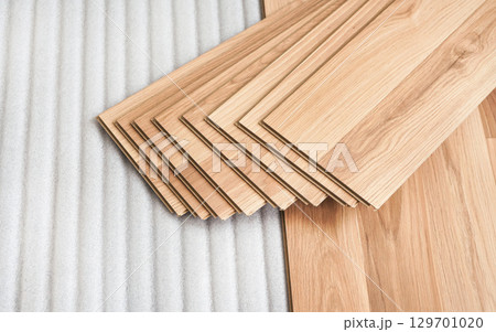 Tiles of laminated floor with wooden effect laying on white base foam, ready to be installed Tiles of laminated floor with wooden effect laying on white base foam, ready to be installed 129701020