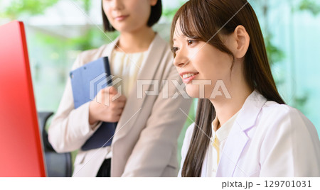 パソコン前で話す二人 パソコン前で話す二人 129701031
