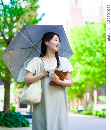 　日傘をさして歩く女子学生のポートレート 129701043