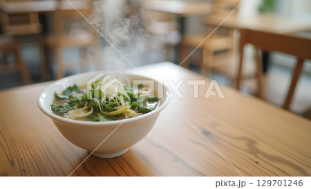 A steaming bowl of delicious ramen on a wooden table in a cozy restaurant setting A steaming bowl of delicious ramen on a wooden table in a cozy restaurant setting 129701246