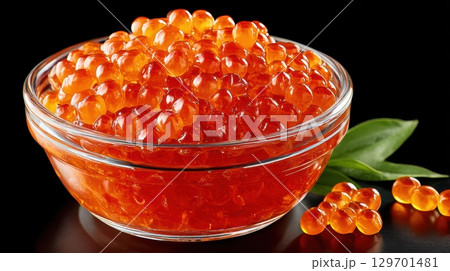 Fresh and Vibrant Sturgeon Caviar in Clear Bowl with Green Leaves on Black Background 129701481
