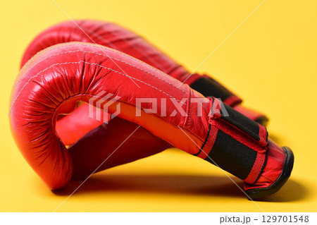 Boxing gloves in red color on yellow background. 129701548