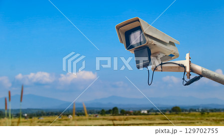 Surveillance Camera on Metal Rail with Blurred Fields Surveillance Camera on Metal Rail with Blurred Fields 129702755