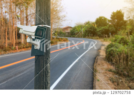 Security Camera on Concrete Pole Over Blurred Road 129702758