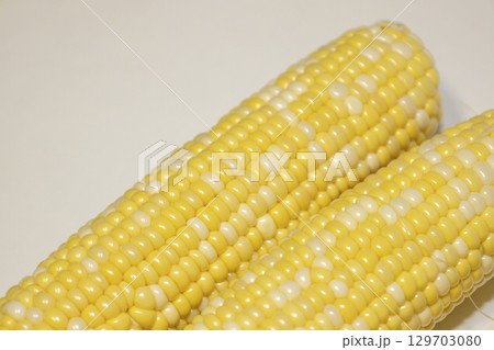 Close raw cobs of sweet corn against background. Tasty sweet corn on cob 129703080