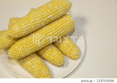 Raw cobs of sweet corn on plate against background. Tasty sweet corn on cobs 129703096