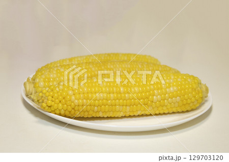 Three cooked cob of sweet corn on white plate against background. Tasty sweet corn on cob. Three cooked cob of sweet corn on white plate against background. Tasty sweet corn on cob. 129703120