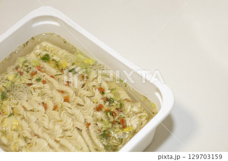 Instant noodles with spices and water on white plastic box. Instant noodles with spices and water on white plastic box. 129703159
