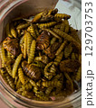 Unique culinary delicacy featuring fried insects in a glass jar at a local market 129703753