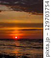 Beautiful sunset over the ocean with vibrant colors reflecting on calm waves at a coastal location 129703754