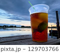Refreshing beverage by the water at sunset, showcasing vibrant colors and evening tranquility 129703766