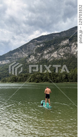 Paddleboarding on Scenic Lake with Mountain Background 129703832