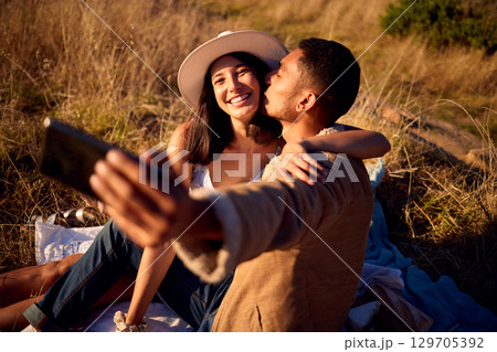 Couple kiss in selfie with hug, outdoor and picnic in nature, love with smartphone, technology and happy together. Phone for photography, man and woman smile in picture with travel and summer date Couple kiss in selfie with hug, outdoor and picnic in nature, love with smartphone, technology and happy together. Phone for photography, man and woman smile in picture with travel and summer date 129705392