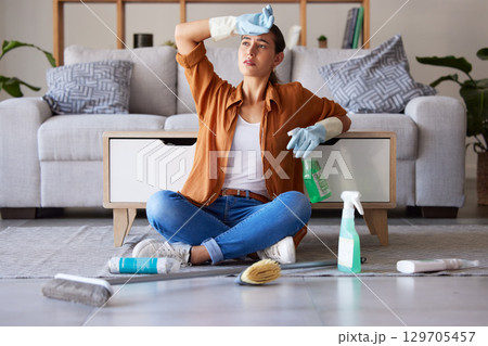 Tired woman, cleaning and sitting on living room floor with detergent, chemicals or sanitizer spray for hygiene at home. Female domestic worker exhausted from housekeeping, chores or clean house 129705457