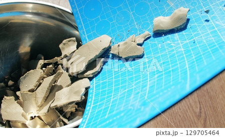 Dried clay fragments collected on a cutting mat for recycling in pottery. Sustainable craft and ceramic material recovery for reuse in handmade production 129705464