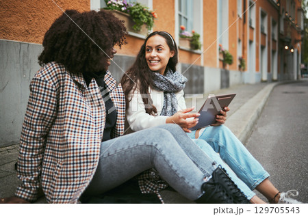 Street, friends and women talking, tablet and social media for connection, conversation and bonding outdoor. Young females, ladies and device for online reading, city and girls on road and discussion 129705543