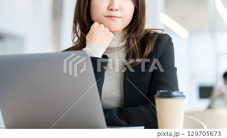 パソコンを使いながら考えごとをする女性・ビジネスウーマン 129705673