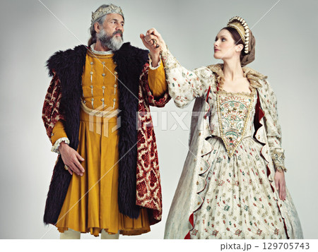 Medieval, love and king with queen in studio on gray background for power, ruler and leadership. History, theatre and isolated royal couple holding hands in vintage, renaissance and Victorian cosplay 129705743