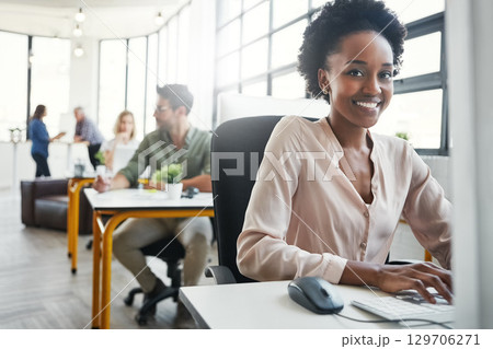 Computer, black woman portrait and business coworking office of a employee by a computer. Lens flare, busy web design workplace and female web designer worker working on a creative project with team Computer, black woman portrait and business coworking office of a employee by a computer. Lens flare, busy web design workplace and female web designer worker working on a creative project with team 129706271