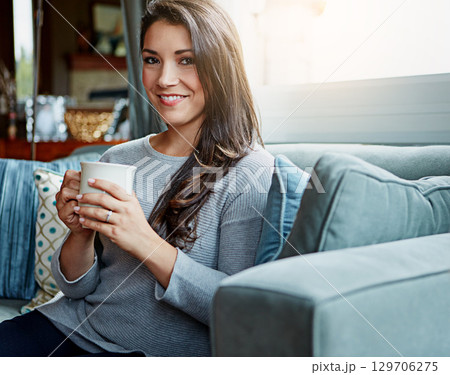 Coffee, woman and portrait of a person at home on a living room sofa with a smile in the morning. Drink, happy person and lens flare on a lounge house couch with tea feeling happiness in a room 129706275